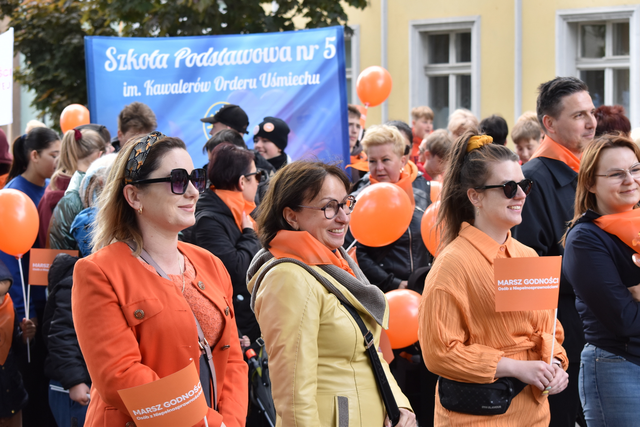 zdjęcie: pracownicy PCPR wraz z Dyrektor Kotarą ubrane w kolorach pomarańczowych idą w mnarszu